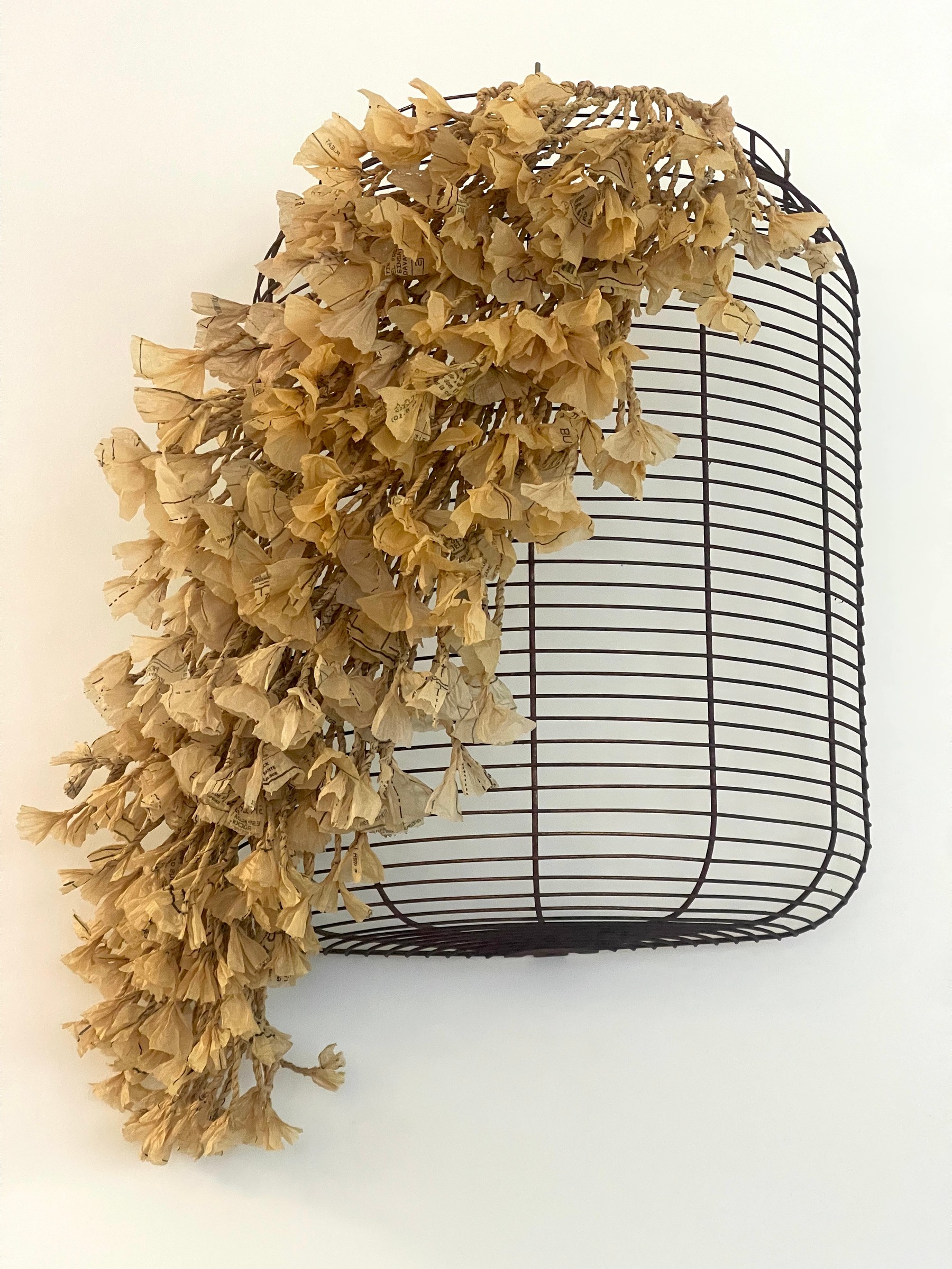 Twisted paper and clustered tissue forms cascade across a curved black heater cover.