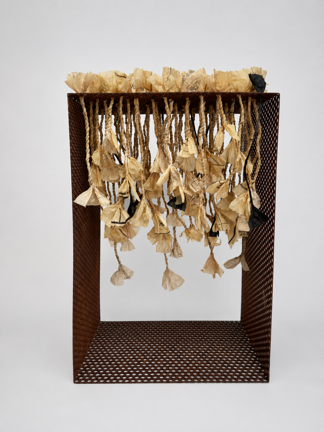 Twisted paper strands ending in flower-like forms hang inside an open metal framework.